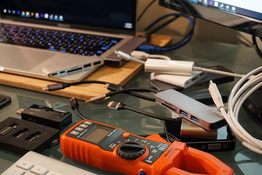 A collection of USB-C hubs and dongles next to a MacBook Pro