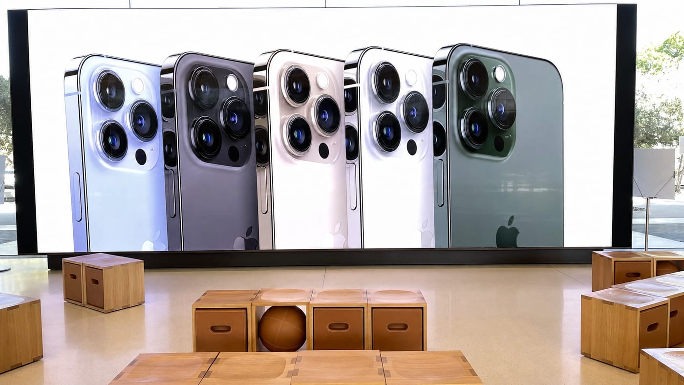 The iPhone Pro camera systems shown across the five colors on an Apple Store video wall.