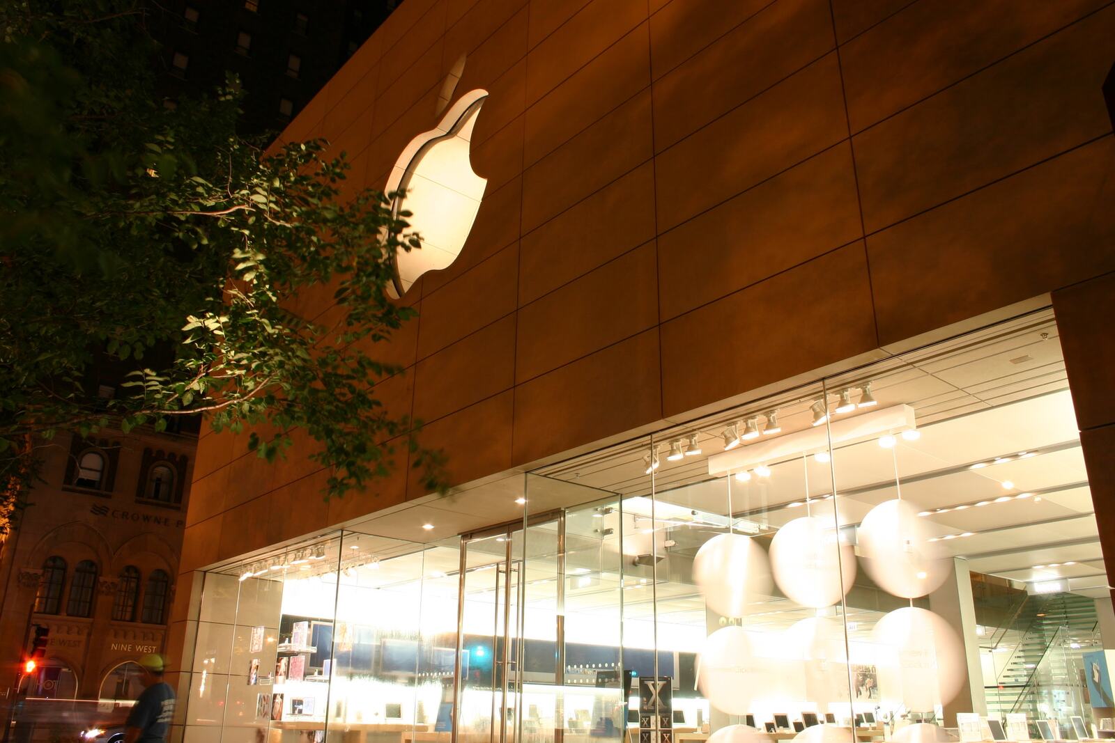 A stone-and-glass storefront at dusk, round lights glowing inside.
