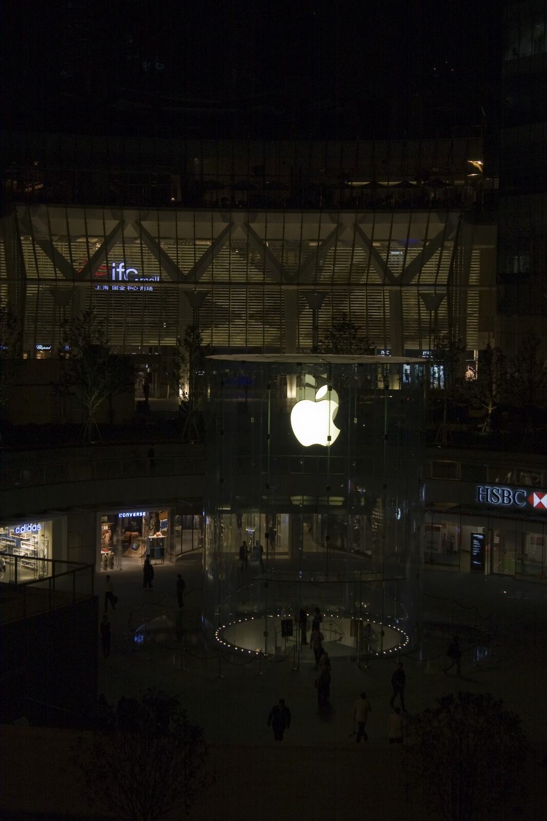 The ifc mall store lit up after dark, the towers of Central rising behind it.