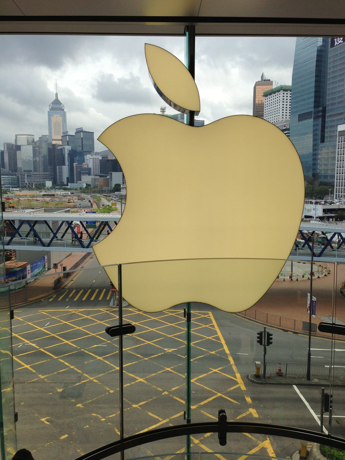 An Apple logo set into a glass wall, a harbour and towers beyond, in Hong Kong.