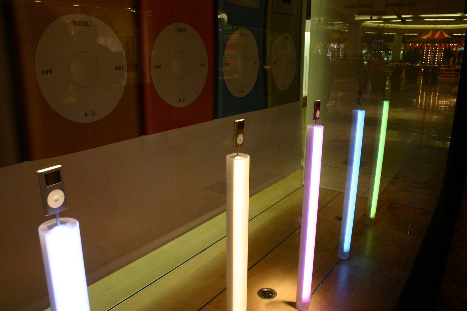 iPod nanos standing on lit columns in the window.