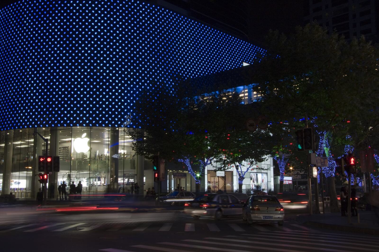 A curved facade lit blue over a night crossing.