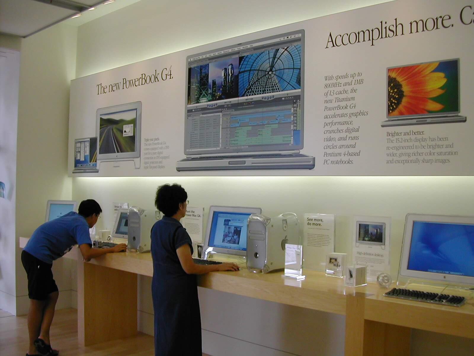 An early store interior: “The new PowerBook G4” along the wall, iMacs on the tables.