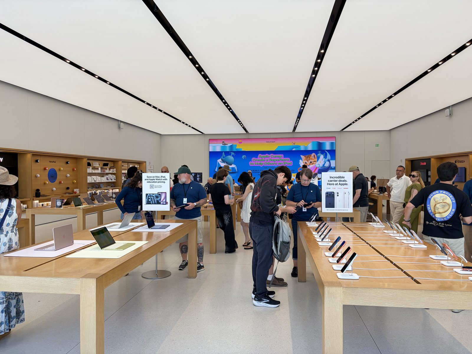 Inside Apple UTC: rows of wood display tables and a Today at Apple session on the video wall.